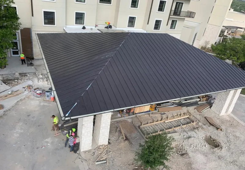 Metal roofing installation team working on a commercial building in Solvay